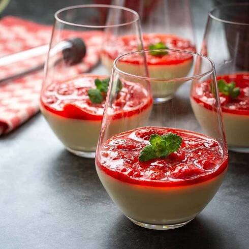 4 glasses with strawberry panna cotta, garnished with mint.