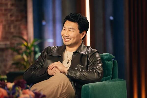 Simu Lui in a blrown letaher jacket, beige pants and a beige T-shrit.