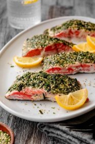 A platter with 4 furikake salmon fillets with lemon wedges on a grey towel.