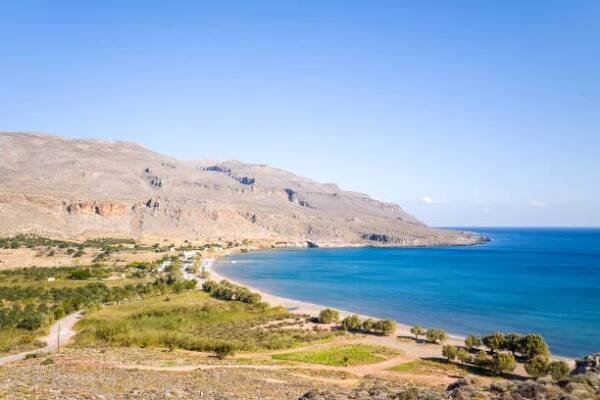 the sandy beach at the foot of the arid mountains , in europe, greece, crete, kato zakros, by the mediterranean sea, in summer, on a sunny day. - achaia - stock snímky, obrázky a fotky