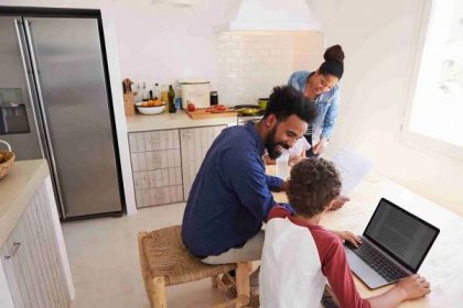 Parents helping kids with homework at table in kitchen — Stock Image