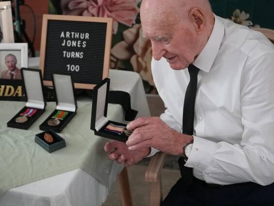 Arthur Jones looking closely at his medals.