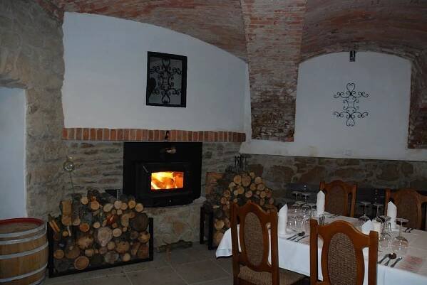 a dining room with a fireplace and a table with a table set with a table at Penzion Bejčkův mlýn in Slavonice
