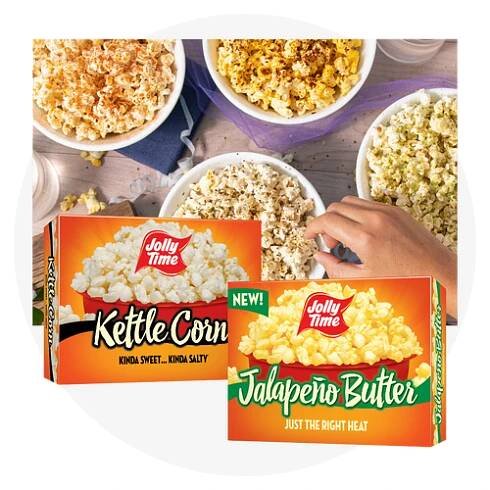 A hand reaching into a bowl of seasoned popcorn with a carton of Kettle Corn and Jalapeno Butter Microwave cartons in front
