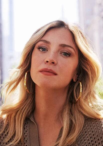 Abby Elliott headshot in gold hoop earrings 