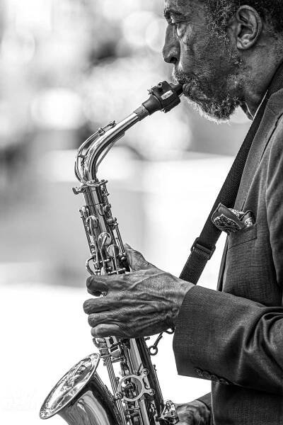 Close up black and white photo of a saxophone player performing.