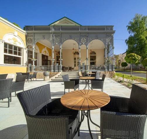 an outdoor patio with chairs and tables and a gazebo at Esplanade, dependance hotelu Monti Spa in Františkovy Lázně