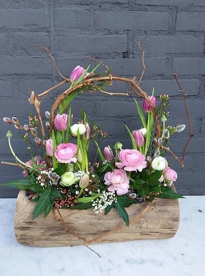an arrangement of pink and white flowers in a wooden basket