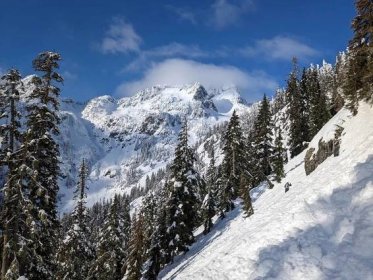 Bezplatný obrázek: Hluboký sníh na svahu v horách s vrcholky hor v pozadí