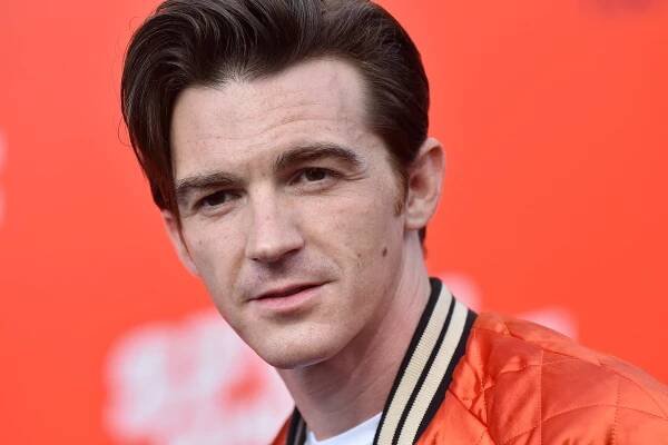 A man in an orange jacket with dark hair.