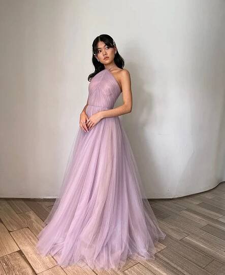 A woman, resembling Momona Tamada, in an elegant, light purple one-shoulder gown stands against a gray background, looking to the side. We’re Head Over Heels For Momona Tamada’s Romantic A-Line Gown is airy with a full skirt.