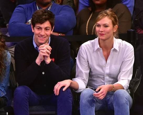 Image may contain Joshua Kushner Karlie Kloss Sitting Human Person Clothing Apparel Crowd Audience and Pants