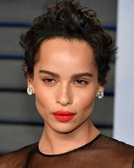 Zoe Kravitz wearing a curly pixie cut with big diamond earrings and red lipstick