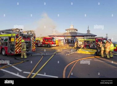 Fire fighters from East Sussex Fire and Rescue Service dampen down the flames following a large fire on the pier in Eastbourne, Stock Photo