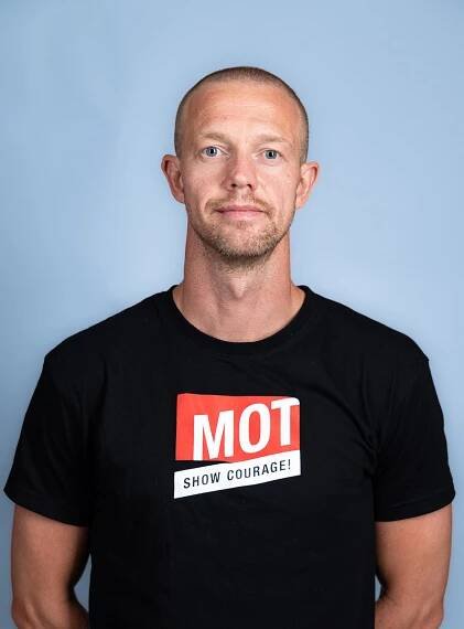 mann i svart t-skjorte ser i kamera