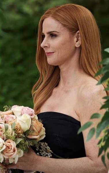 a woman holding a bouquet of flowers in her hand and looking away from the camera
