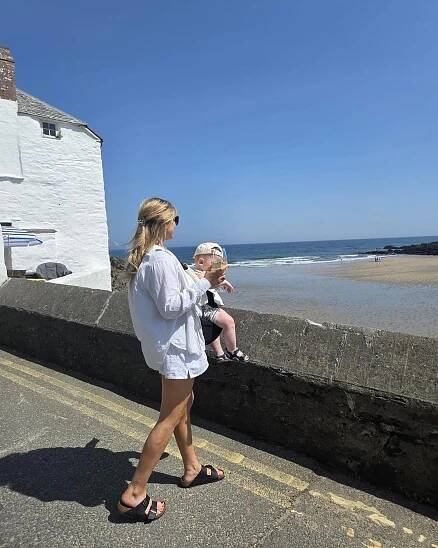Woman and child at the beach; woman holding a drink.