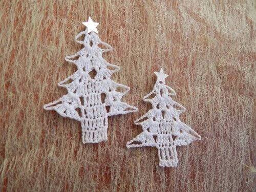 two small crocheted christmas trees sitting on top of a wooden table next to each other