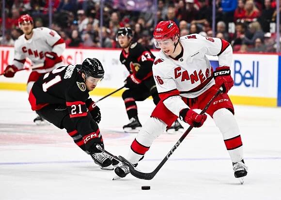 Carolina Hurricanes player #56 battles an Ottawa Senators player for the puck.