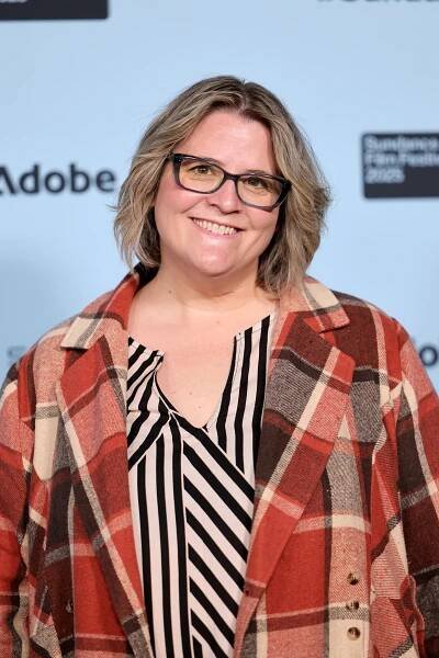 Person smiling in a checkered coat and striped shirt at a film festival event
