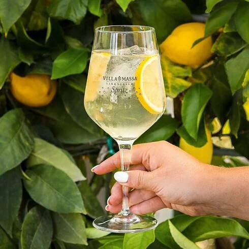 Hand holding a glass of Villa Massa Limoncello Spritz.