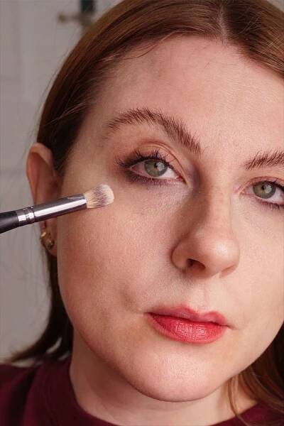 Person applying Tarte Shape Tape Concealer under their eye with a brush