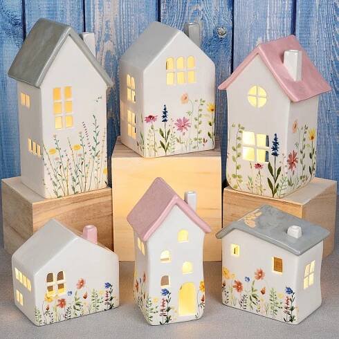 five small houses are lit up on wooden blocks with flowers and plants painted on them
