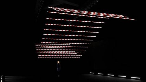 Barrier Bars je kinetická instalace 24 červenobílých tyčí tančících v černém prostoru – DesignVid.cz