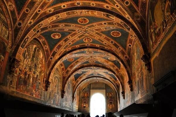 A ceiling with colorful frescoes painted on it, and lines in geometric patterns criss-crossing it.