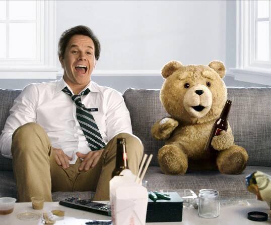 Mark Wahlberg and Ted the bear sitting on a couch, drinking beer.