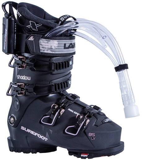 Surefoot Lange Shadow 85 LV matte black ski boot shell with light pink accents on buckles and Lange logo in black on power strap, Surefoot logo in light pink. Plastic tubes coming out for Surefoot memory foam injection into shell lining. Winterheat ski boot heater attached to outside edge.