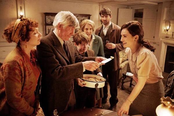 THE GUERNSEY LITERARY AND POTATO PEEL PIE SOCIETY, (AKA THE GUERNSEY LITERARY & POTATO PEEL PIE SOCIETY), FROM LEFT: KATHERINE PARKINSON, TOM COURTENAY, KIT CONNOR, PENELOPE WILTON, MICHIEL HUISMAN, LILY JAMES, 2018. PH: KERRY BROWN/© NETFLIX