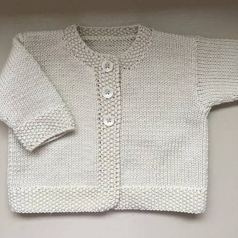 a white knitted sweater with buttons on it