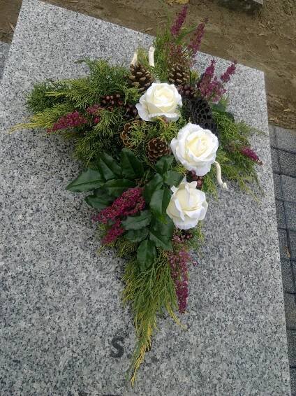 white roses and greenery are placed on a granite slab