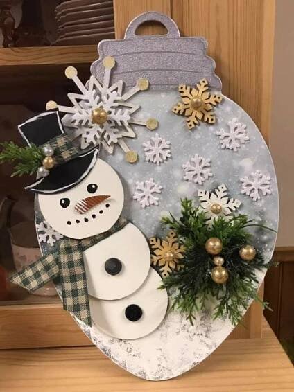 a snowman decoration hanging from the side of a wooden door with christmas decorations on it
