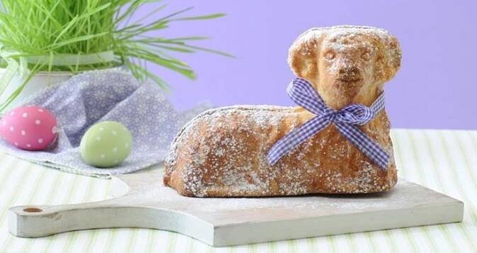 a loaf of bread shaped like a dog with a blue bow on it's neck