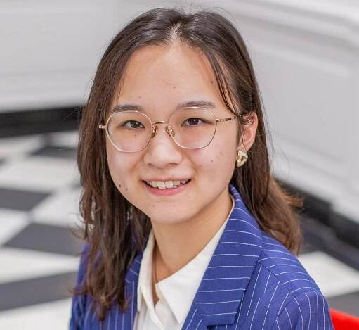 person with long brown hair and glasses wearing a blue blazer