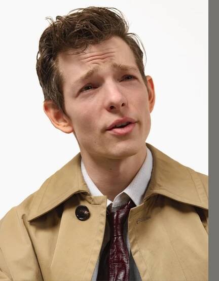a young man wearing a trench coat and tie
