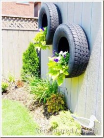 Kvetoucí květináč na pneumatiky namontovaný na stěně