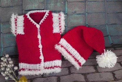 a knitted red sweater and hat sitting on top of a brick floor next to flowers