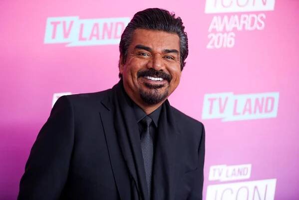 A smiling man with a mustache and goatee wearing a dark suit, shirt and tie