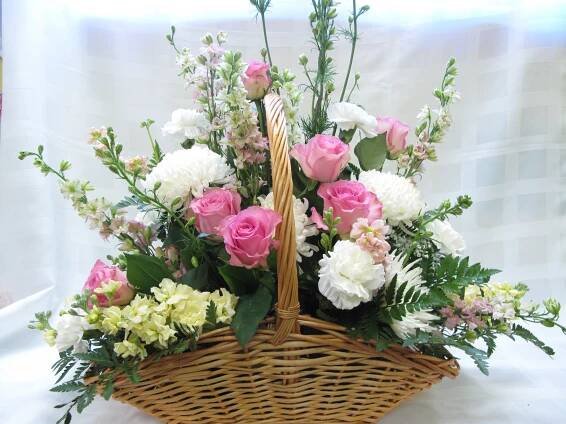 a basket filled with lots of flowers sitting on top of a white cloth covered table