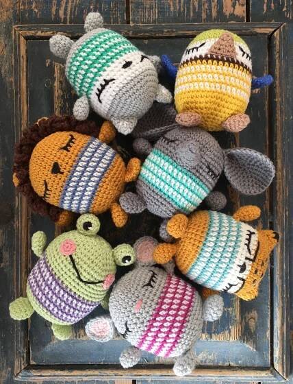 several crocheted stuffed animals sitting on top of a wooden door frame, all wearing hats and scarves