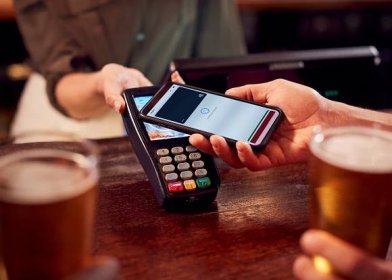 Close-up of a man paying at a bar using contactless app.