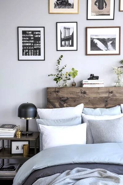 a bed with white sheets and pillows in front of pictures on the wall above it