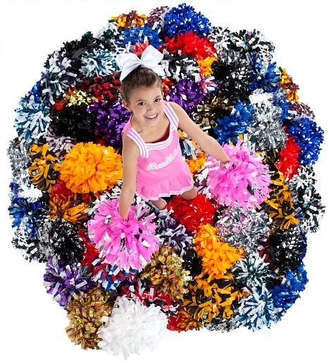 young cheerleader in a pink uniform standing in a pile of colorful poms