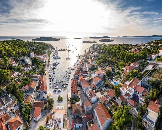 Letecký záběr na marínu maslinica, domy s oranžovou střechou a zakotvené lodě