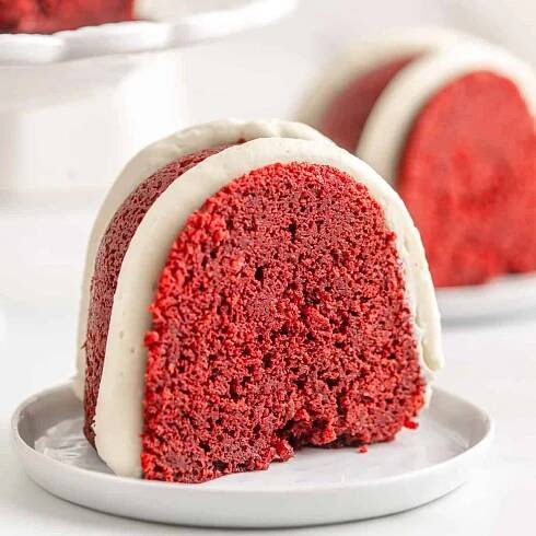 A close up of a slice of red velvet pound cake on a white plate.