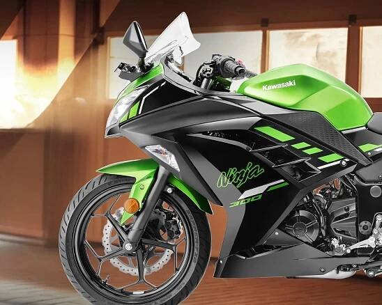 Sporty Kawasaki Ninja 300 motorcycle in green and black, showing the front wheel, headlight, and part of the fuel tank with the Kawasaki logo. The bike has aerodynamic fairings with "Ninja" and "300" decals.