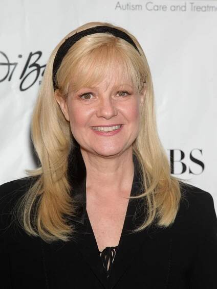 a woman with blonde hair wearing a black shirt and headband smiles at the camera